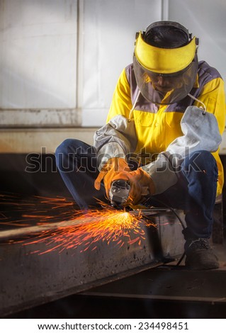 Worker hard work Electric wheel grinding on steel structure in factory with dramatic light