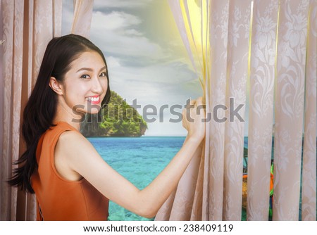 Young asia woman opens the curtains with her dream destination phuket Thailand