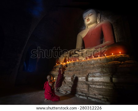 Big buddha statue and Mini Monk in meditation inside temple in Bagan Mandalay Myanmar