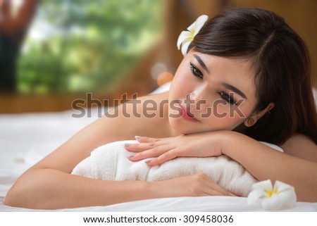 beautiful spa woman lying on the couch, out door is green nature and rolled towel