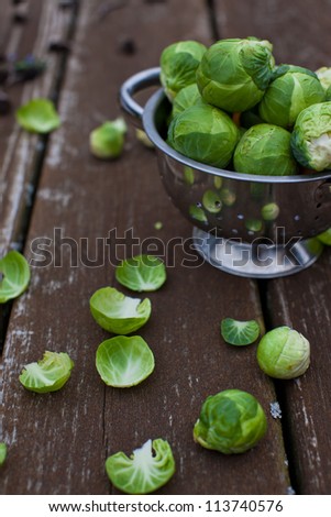 Brussels sprouts in a metal colander on wooden surface