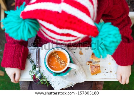 Kid in Christmas Hat holding a Mug of Tomato Soup with Seeds. Also available in vertical format.