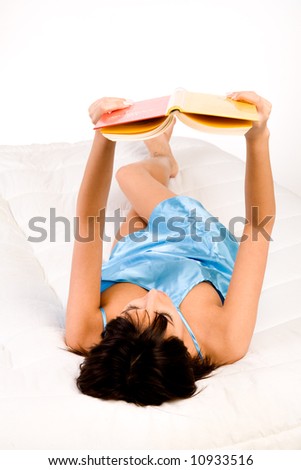 Brunette in pyjama\'s reading a book in bed