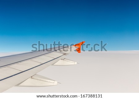 Wing of an airplane flying above the clouds. people looks at the sky from the window of the plane, using airtransport to travel.