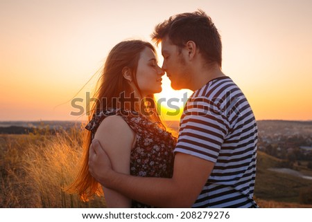 Young couple in love outdoor. Stunning sensual outdoor portrait of young couple posing in summer sunset in field