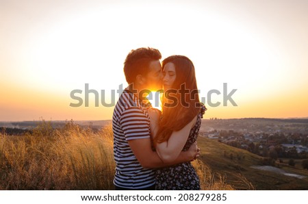 Young couple in love outdoor. Stunning sensual outdoor portrait of young couple posing in summer sunset in field