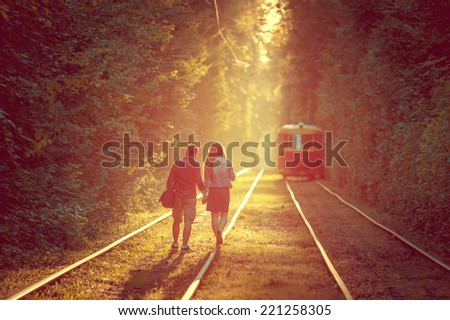 romantic young couple walking along the tram tracks in high forest