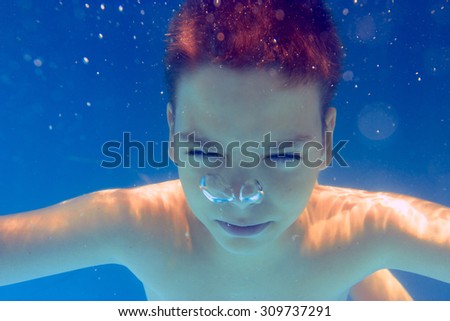 Underwater close-up portrait of cute boy in the swimming pool.