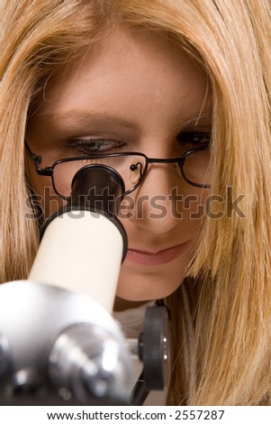 a medical scientist / doctor, examining something under a microscope.