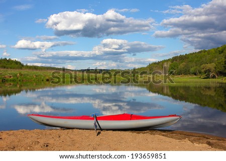 red inflatable kayak on the sandy shore, river Ugra, Russia