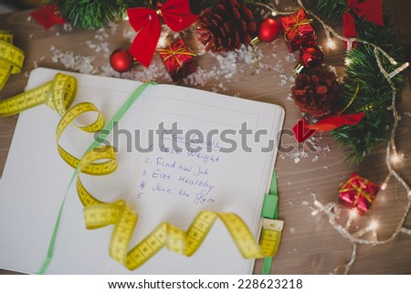 New year\'s resolutions written on a notepad with a measure tape