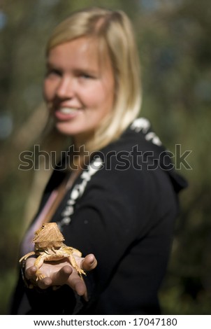 Female standing with arm out and bearded dragon in palm of hand