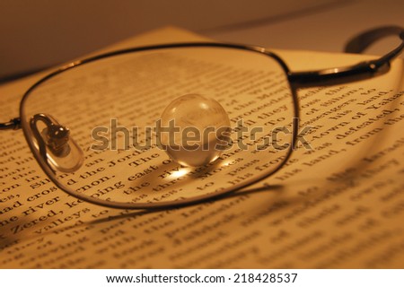 Glass Marble through Glasses Lens on Book - Metaphor for Inspiration, Insight