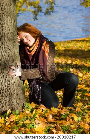 The young girl about a tree in autumn park