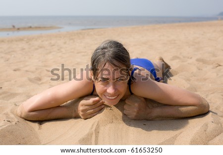 The woman plays with sand on summer beach