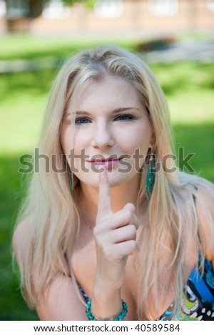 Pretty young sexy woman holding finger near her mouth showing to stop talking