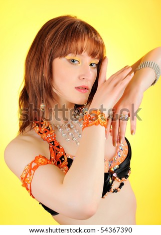 Beautiful mystic woman with golden make-up in belly dance costume. yellow background