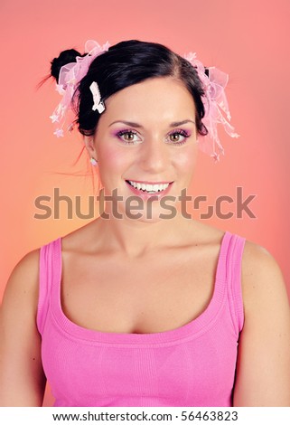 Beautiful happy smiling woman with natural make-up and funny hairstyle . pink background