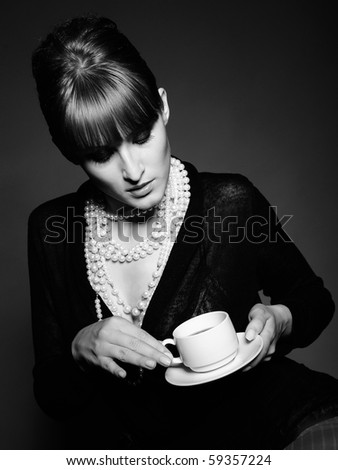 Beautiful retro woman with red lips holding cup of coffee. black and white picture