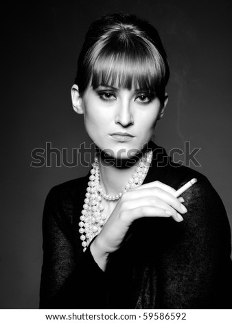 Beautiful retro woman with red lips holding cigarette and smoking. black and white picture