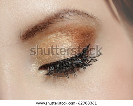 Beautiful macro shot of eye with long lashes and make-up in brown tones