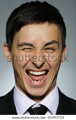 Portrait of funny young business man winking. expressions on gray background