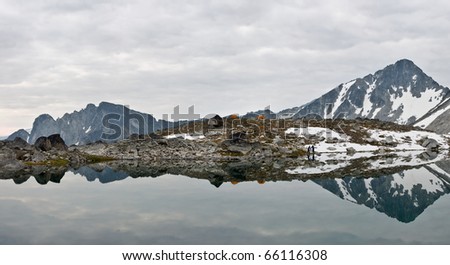 Two people camped at the shores of an alpine wilderness lake