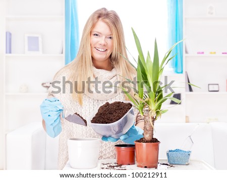 Happy blond woman transplant plant in a bigger pot