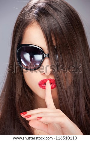 pretty brunette woman showing the sign for silence with her index finger