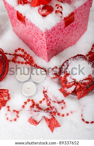 Christmas gift box in the snow with red balls and candles