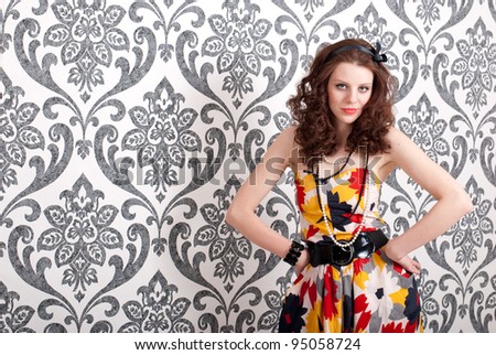 Young beautiful woman in retro dress on vintage wallpaper background