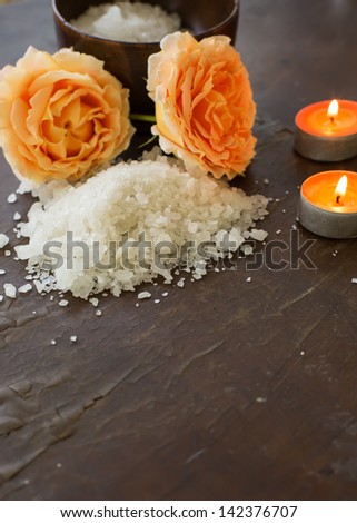 Sea salt in bowl with rose and candles on wooden background.  Selective focus.Spa/wellness products.