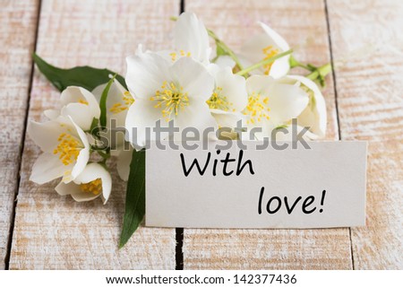 Postcard with fresh flowers and tag with words With love.