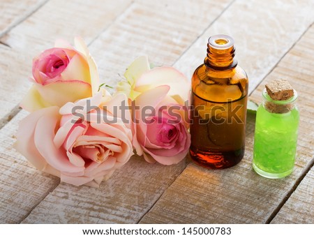 Essential aroma oil with roses on wooden background. Selective focus.