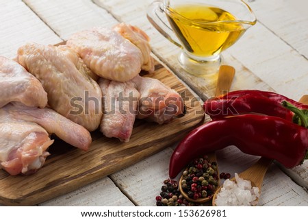 Fresh raw chicken wings on wooden board on white table. Selective focus.