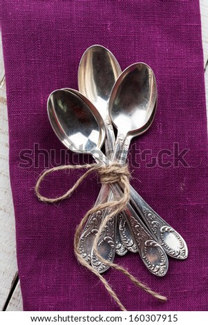 Vintage silver spoons on napkin on wooden background.
