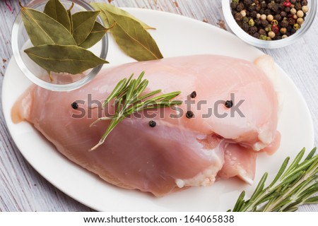 Fresh chicken meat on plate on white wooden  table. Selective focus. Rustic style.