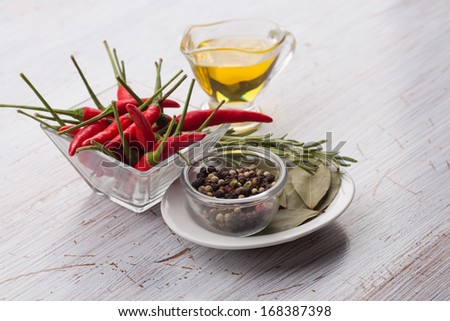 Mixed pepper, chili, bay leaves, oil  on wooden background.Selective focus.