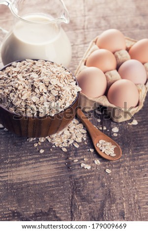 Oat flakes, eggs, milk on wooden table. Selective focus.
