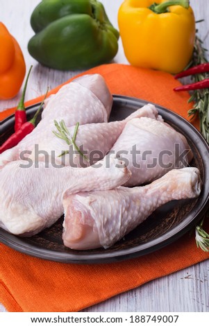 Fresh chicken meat on plate on white table with vegetables. Selective focus. Rustic style.