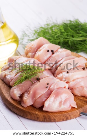 Fresh chicken meat on wooden board on table. Selective focus, vertical.