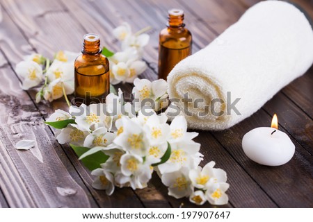 Spa setting on wooden background. Towel, aroma oil, candle, flowers. Selective focus, horizontal.