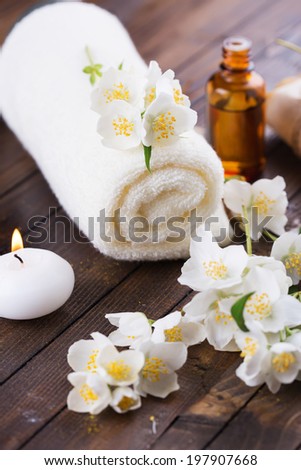 Spa setting on wooden background. Towel, aroma oil, soap, candle, flowers. Selective focus, vertical.