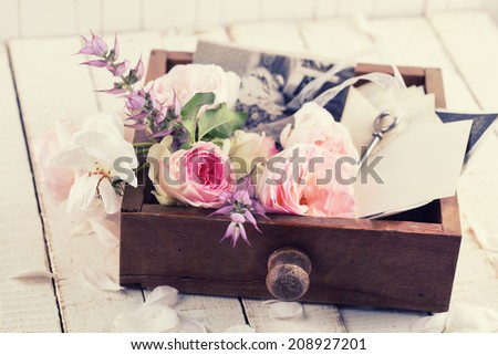 Box with flowers and old photos  on wooden background. Selective focus.
