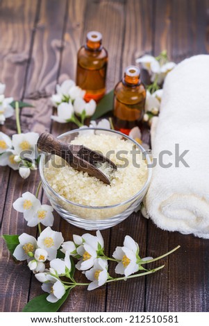 Spa setting.Sea salt, essential aroma oil with jasmine  on wooden background. Selective focus.
