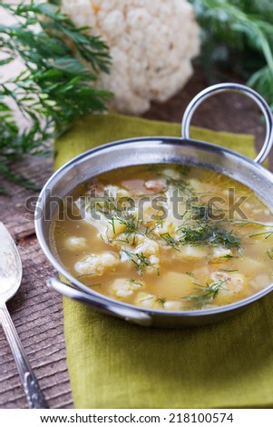 Soup with vegetables cauliflower, potato, onion in bowl on wooden background. Selective focus, vertical.