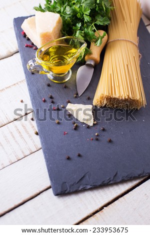 Italian food - cheese parmesan, raw pasta, olive oil  on slate  on white table. Selective focus.