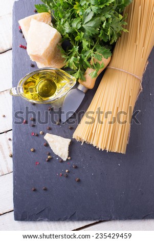 Italian food -  raw pasta, cheese parmesan,  olive oil  on slate  on white table. Selective focus.