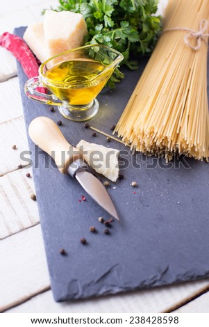 Italian food - raw pasta,  cheese parmesan, olive oil  on slate  on white table. Selective focus.
