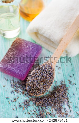 Lavender spa. Dry lavender buds in spoon and soap on green painted wooden planks. Selective focus.